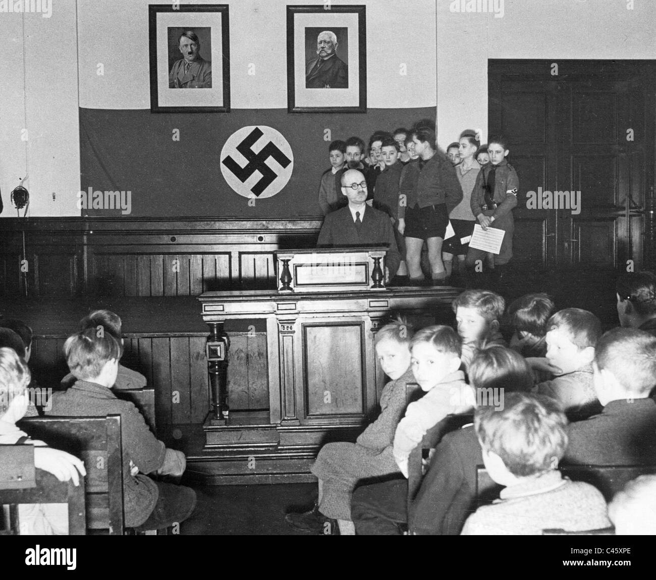 Weitere Schulklasse mit Hakenkreuz an der Wand. Ein Kind trägt es auch