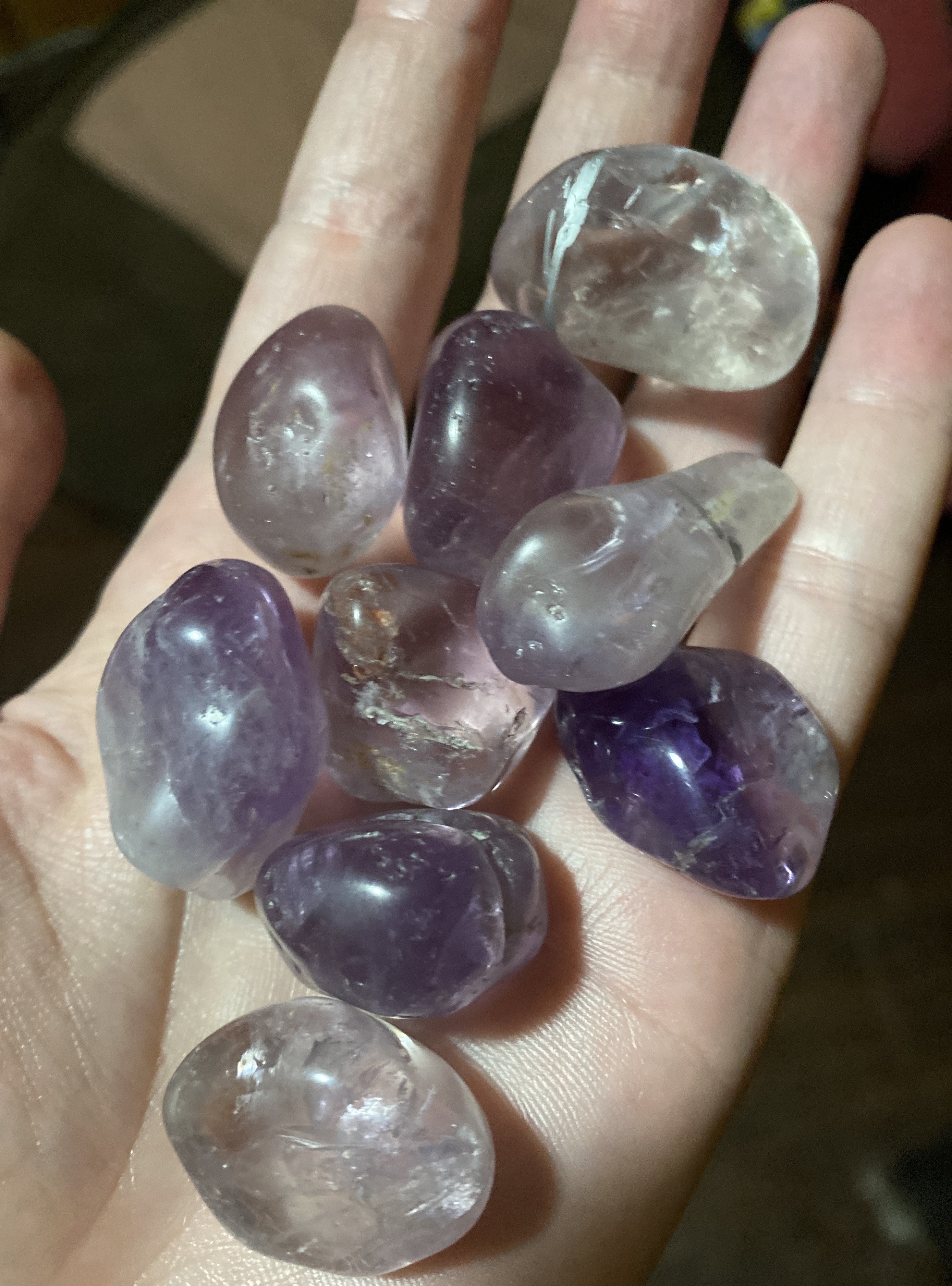 9 translucent rocks ranging from clear to purple, held in someone's left palm